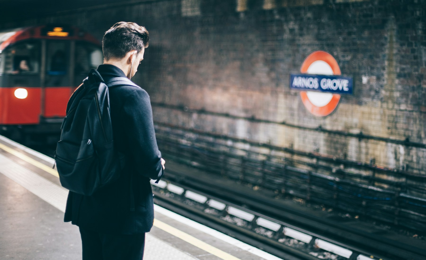 Commuter with a backpack waiting on a train platform