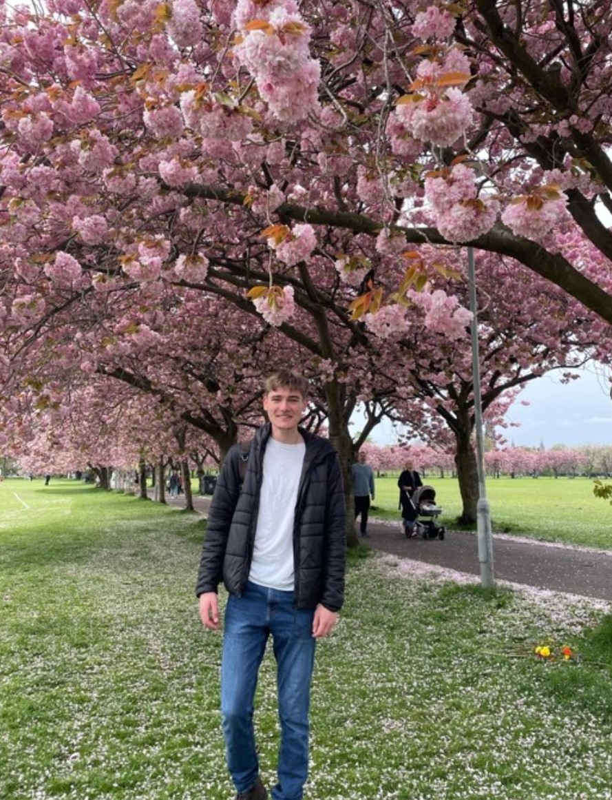 Garret standing beneath flowering trees in Edinburgh