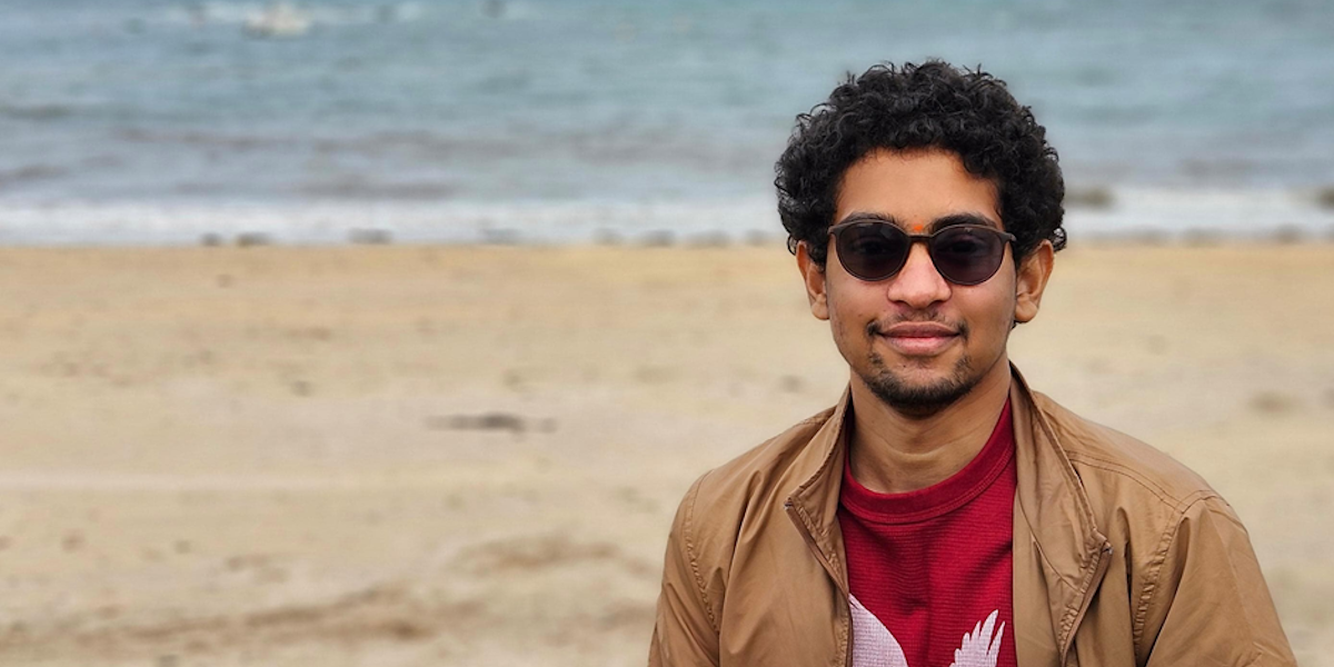 Sri sitting on rocks beside the sea